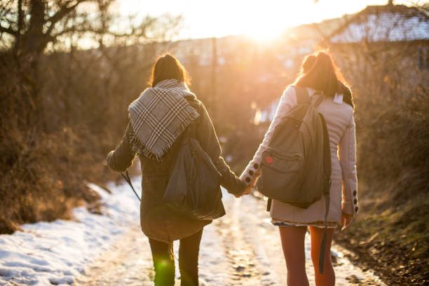 2 women waking hand in hand in winter landscape 2 women waking hand in hand in winter landscape