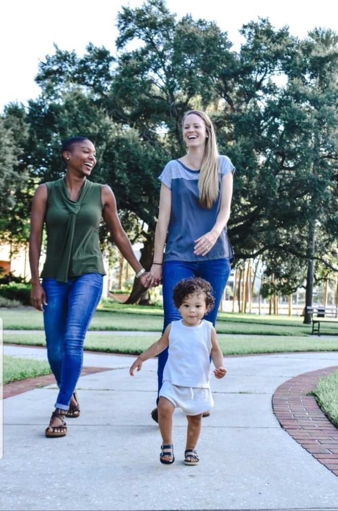 Lesbian couple walking in park with toddler Lesbian couple walking in park with toddler