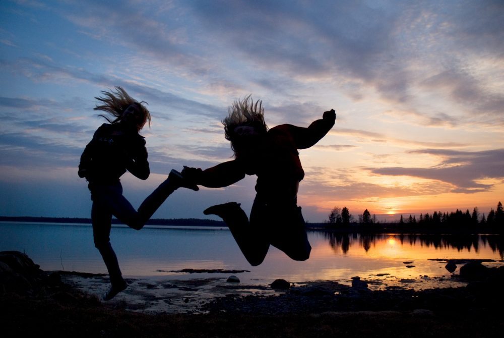 2 sillouettes jumping up against sun set 