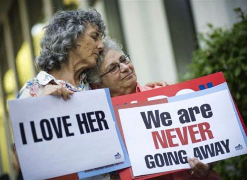 2 older Lesbians holding up signs 
