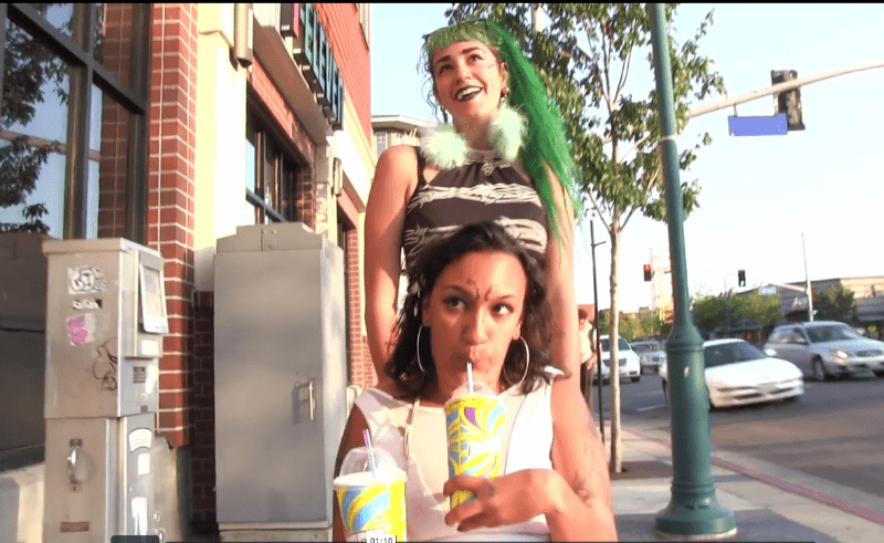 Woman with green hair pushes a woman in a wheelchair