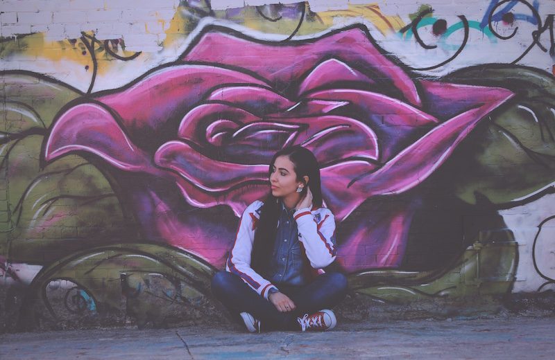 Young woman sitting in front of graffiy wall